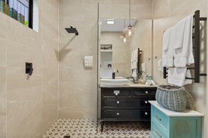 A modern bathroom with a large mirror, a sink, and a vanity. - Jardin Tiny House (Beechmont)