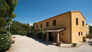 A yellow building with a gravel driveway and a covered patio area. - LE PESCINE - Casa Oliveta: Spighe [OP] (Vada)