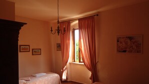 A room with two beds, a chandelier, and a window with curtains. - LE PESCINE - Casa Oliveta: Spighe [OP] (Vada)