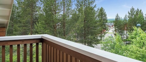 A wooden deck with a view of a forest and a distant building.