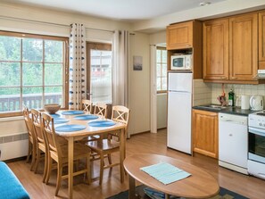 A compact kitchen with wooden cabinets, a microwave, a refrigerator, and a stove. - Levin alppi 2 as 5 by Interhome (Kittilä)
