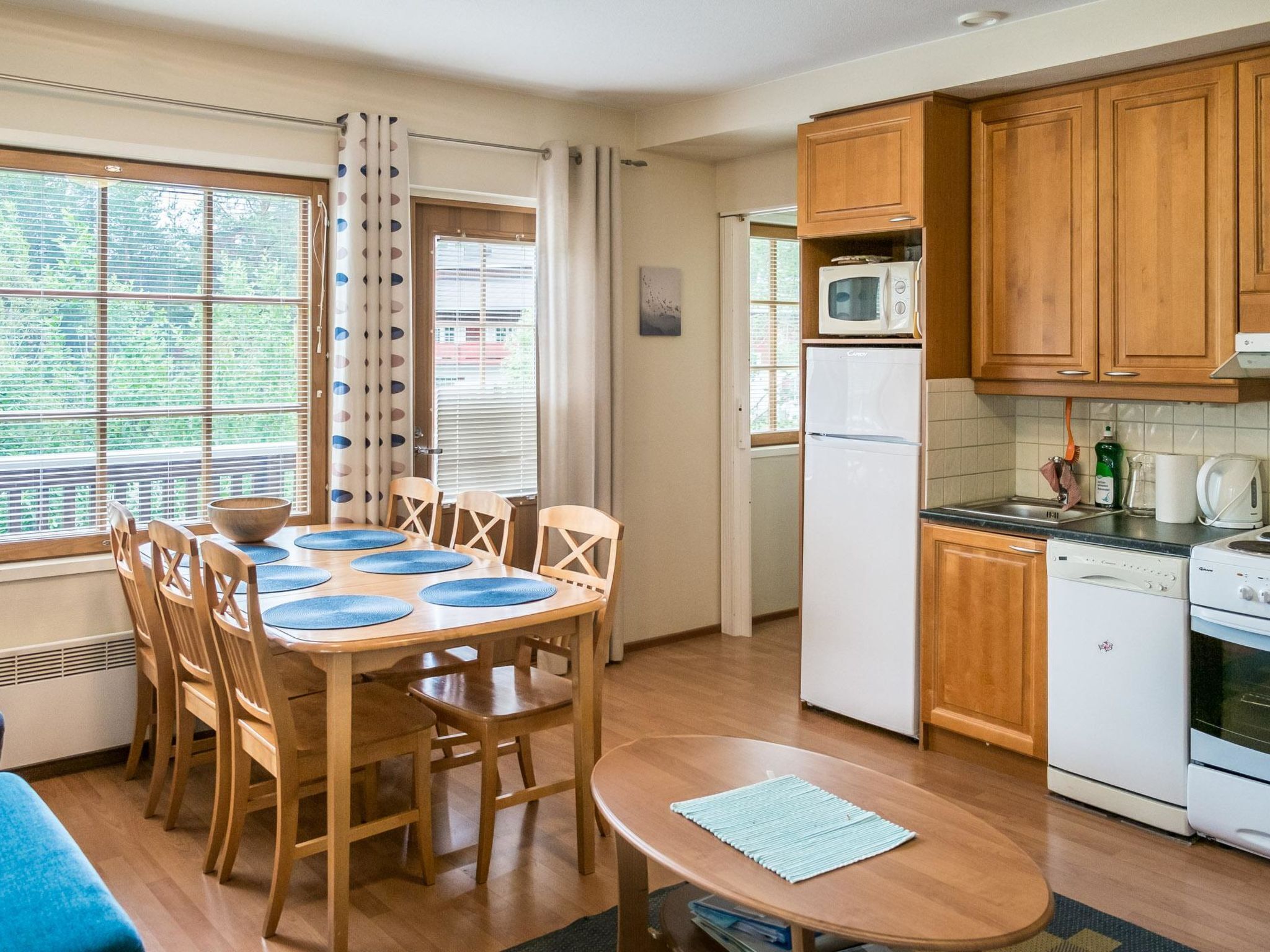 A compact kitchen with wooden cabinets, a microwave, a refrigerator, and a dishwasher.