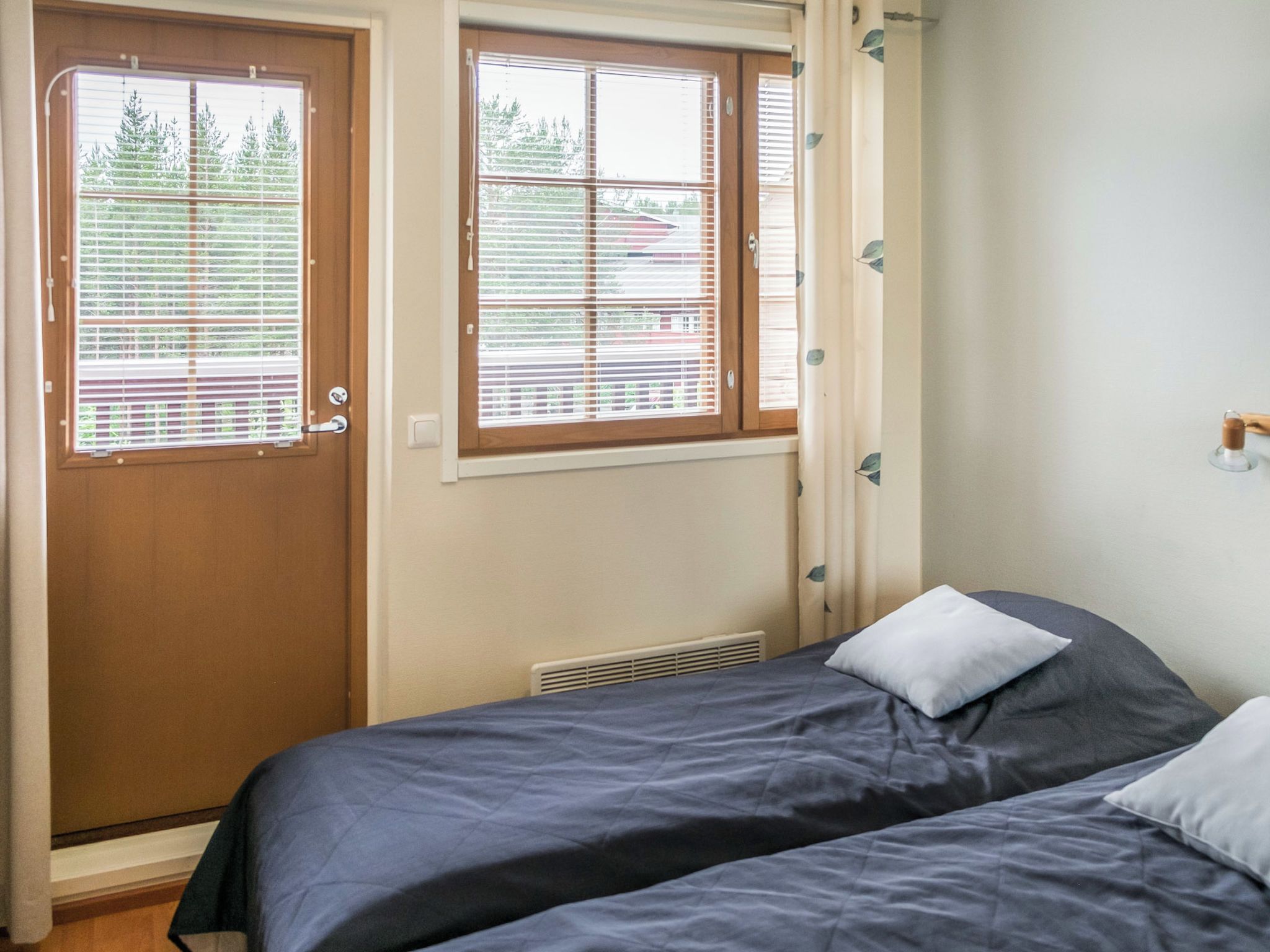 Un dormitorio con dos camas, una puerta con ventanal y un radiador.