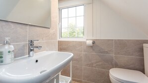 Ein Badezimmer mit einem weißen Waschbecken, einer Toilette und einem Fenster.