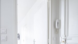 A hallway with white doors, a light switch, and a thermostat on the wall. - Gorgeous Paris EIFFEL TOWER (Paris)