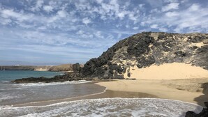 Ein Strand mit felsigen Klippen und ruhigen Wellen.