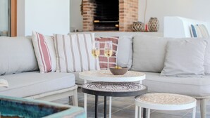 Ein gemütlicher Wohnbereich mit einer Couch, zwei runden Tischen und einem Kamin aus Ziegeln.