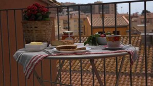 Ein Balkon mit einem Tisch, gedeckt für eine Mahlzeit, einschließlich Brot, Butter und einem Marmeladenglas.