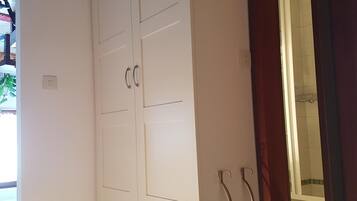Una habitación con armarios blancos, una pequeña mesa redonda y un espejo con marco de madera.