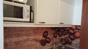 Una cocina con armarios blancos, protector contra salpicaduras de madera, una cafetera y un microondas integrado.