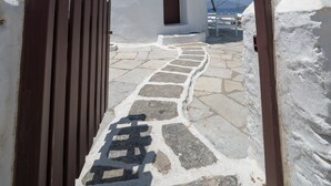 A white windmill with a stone pathway leading to a wooden door. - Unique accommodation in one of the island's iconic windmills (Mikonos)