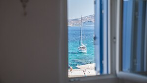 A view of a sailboat on the water through a window with blue shutters. - Unique accommodation in one of the island's iconic windmills (Mikonos)