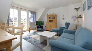 Un salon avec une table à manger en bois, un canapé bleu et un téléviseur.