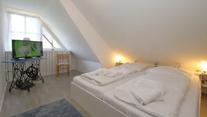 Une chambre à coucher avec un lit, un téléviseur posé sur une table, une chaise et une fenêtre.