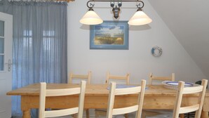 Un coin repas avec une table et des chaises en bois, un lustre, un tableau et une horloge murale.