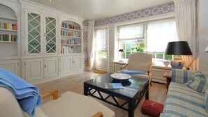 A cozy living room with a sofa, a coffee table, and a bookshelf. - Welcome to Haus Ruusenhoog, the versatile vacation home located in picturesque Braderup (Braderup)