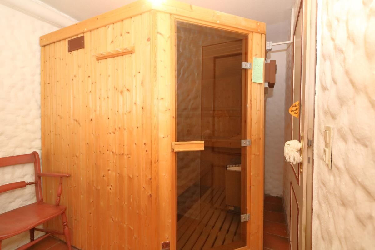 A wooden sauna with a glass door, a bench, and a towel rack.