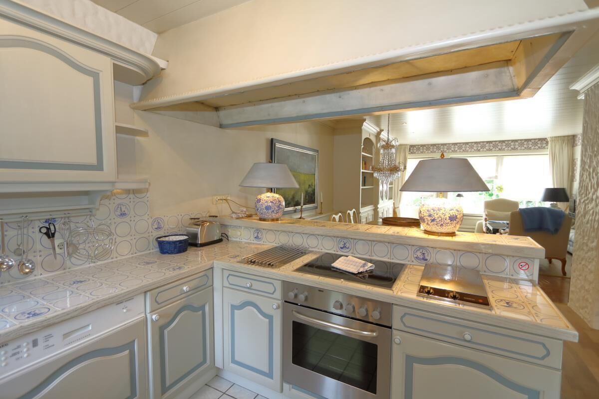 Uma cozinha com armários brancos, forno embutido e fogão.