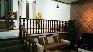 Un salon avec un escalier, un canapé, une télévision et une plante.