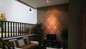 Un salon avec un canapé, un meuble pour la télévision et des plantes décoratives.