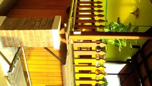 Un escalier en bois à plusieurs niveaux, doté d’une rampe, d’un mur végétal et d’une plante suspendue.