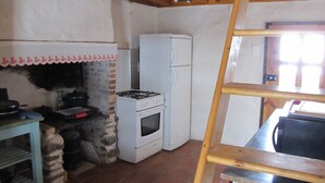 A kitchen with a gas stove, a refrigerator, and a stone oven. - Welcome to Hautes-Pyrénées (Campan)