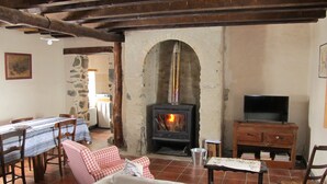 A rustic living room with a stone fireplace, wooden furniture, and a television. - Welcome to Hautes-Pyrénées (Campan)