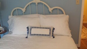 A bed with a white headboard and a decorative pillow. - Chestnut Lane Bed & Breakfast - The Blue Room (New Glasgow)