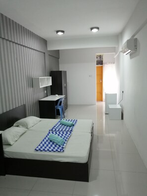 A modern hotel room with a bed, a desk, a wardrobe, and a bathroom.