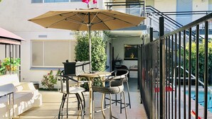 An outdoor patio with a table and chairs, a large umbrella, and a pool in the background. - 3BR Condo SALE nexttoSTRIP nearLVCC sale modern stylish WiFi pool Labor Day Sema (Las Vegas)