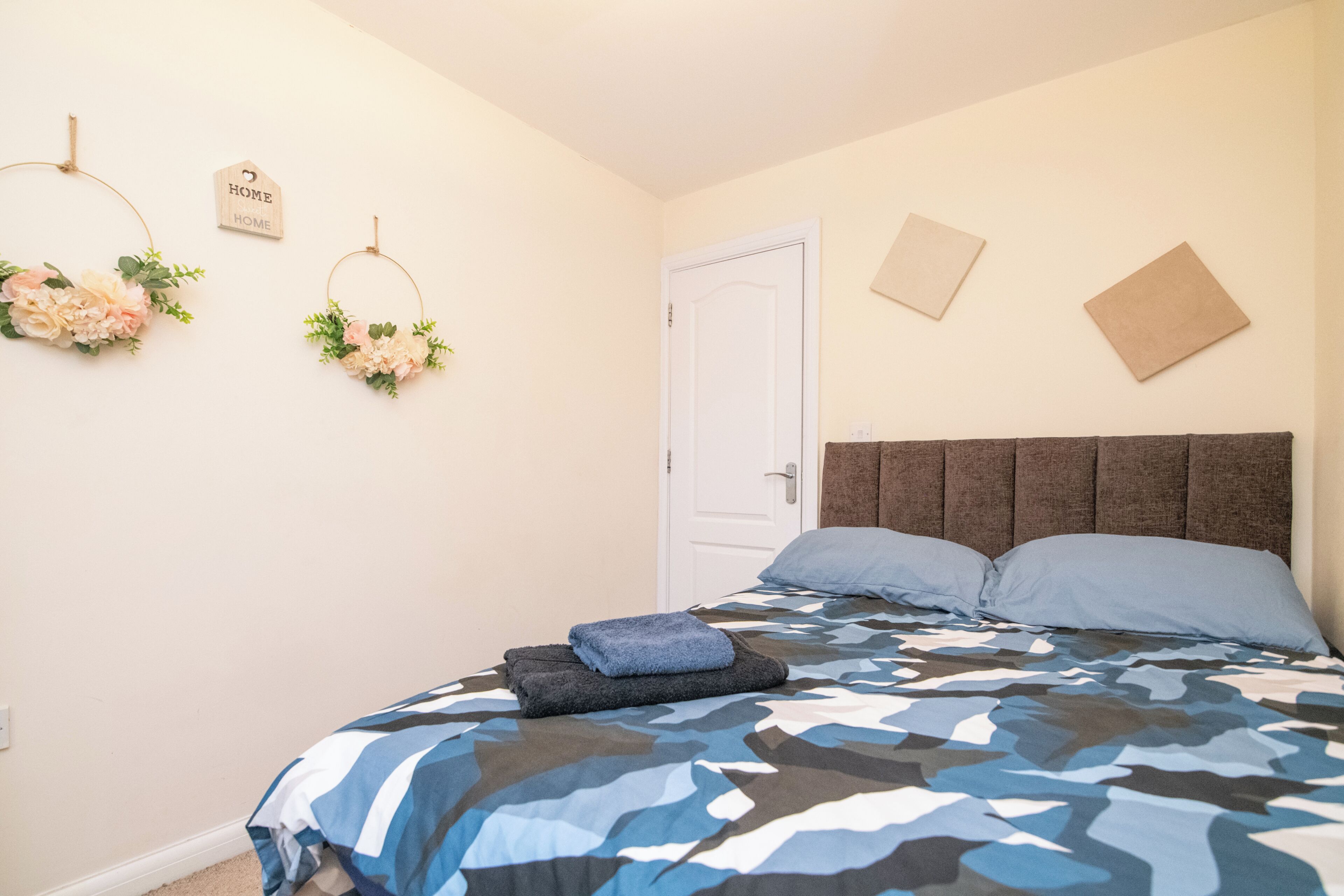 A bedroom with a bed, a door, and wall decorations.