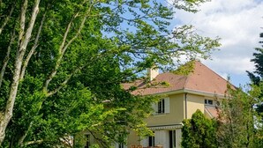 A two-story house with a red-tiled roof, surrounded by lush greenery and trees. - A spacious vacation rental perfect for family getaways: games, nature, and tranquility (Villotte-sur-Aire)