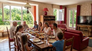 A family dining room with a large table, chairs, a television, and a red sofa. - A spacious vacation rental perfect for family getaways: games, nature, and tranquility (Villotte-sur-Aire)