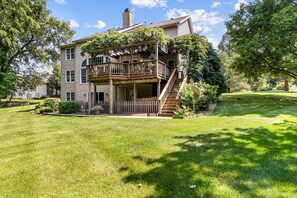 A two-story house with a wooden deck and a covered porch.