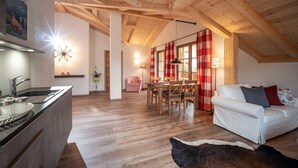 A cozy interior with a wooden ceiling, a dining area, a white sofa, and a kitchen with a sink and countertop. - Apartment Kranzhorn, 75sqm, balcony (Oberaudorf)