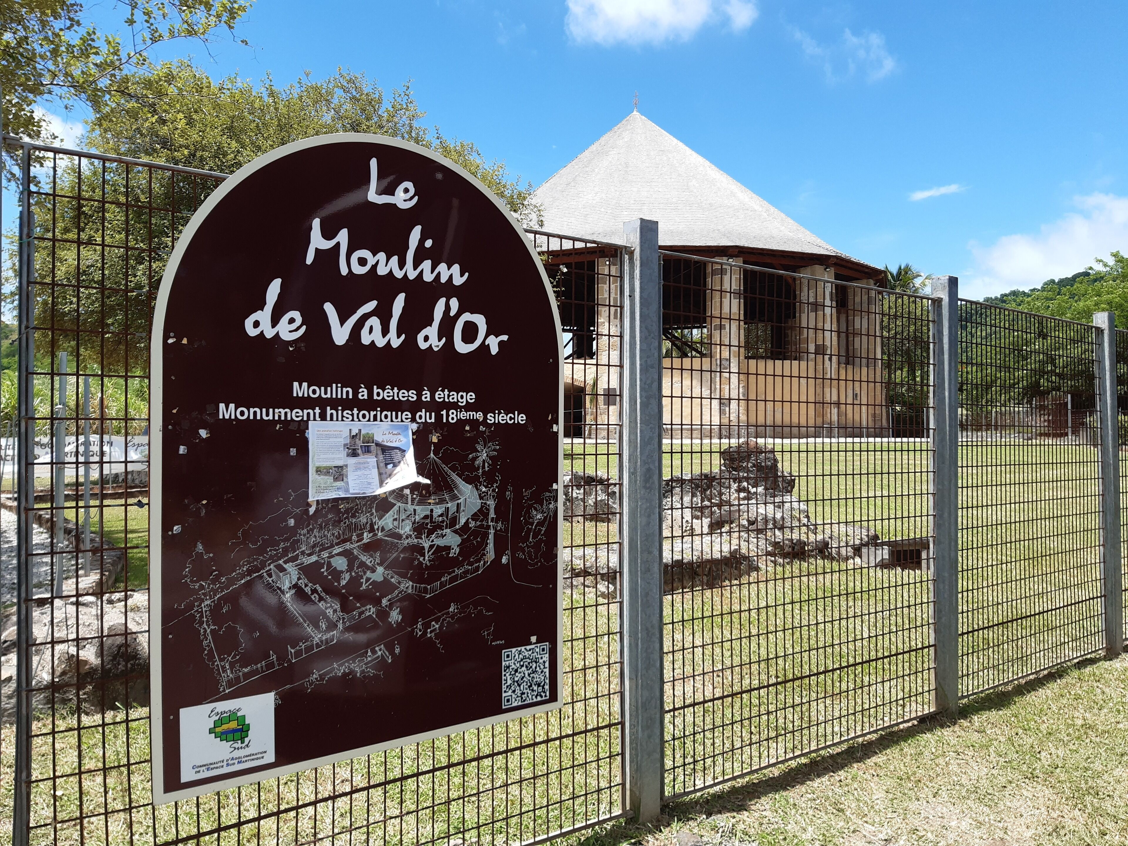 A historical site with a signboard and a fenced area.
