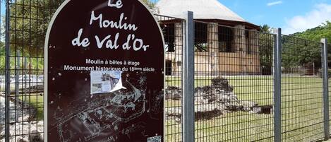 A historical site with a signboard and a fenced area.