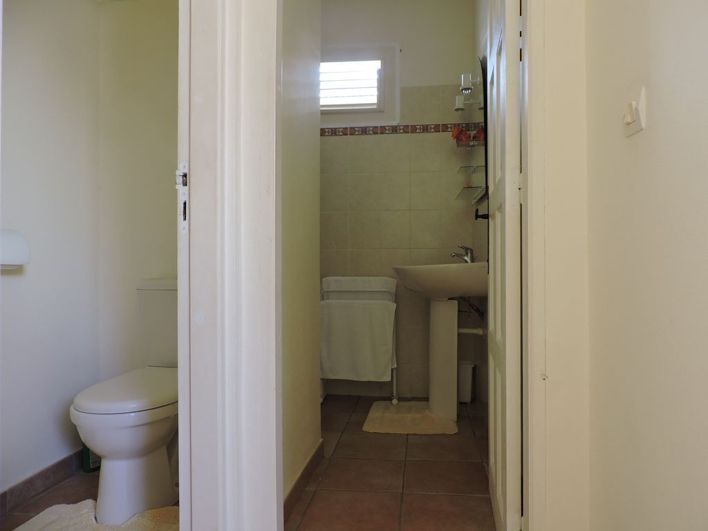 Een smalle gang die leidt naar een badkamer met toilet, wastafel en handdoekrek.