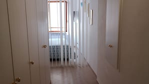 A hallway with white walls, a tiled floor, and a bed with a patterned bedspread in the background. -  Apartment in Riomaggiore / Cinque Terre (Riomaggiore)