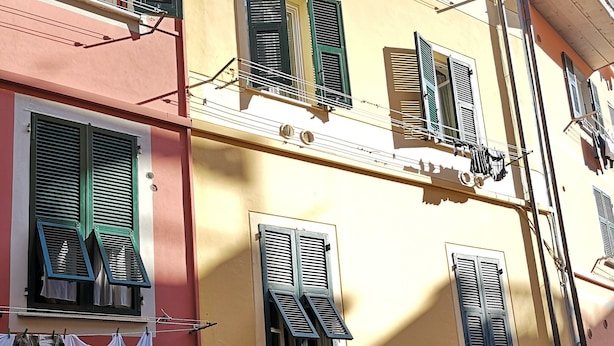 A multi-story building with balconies, a ground-level shop with various items for sale, and a sign indicating a pizza place. -  Apartment in Riomaggiore / Cinque Terre (Riomaggiore)