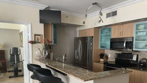 A modern kitchen with a central island, stainless steel appliances, and bar stools.
