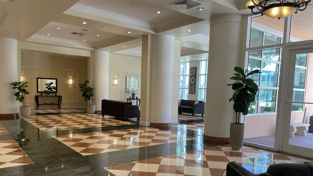 A lobby with a checkered floor, large columns, and a seating area with a sofa.