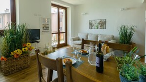 A dining area with a wooden table, chairs, a TV, and a sofa.