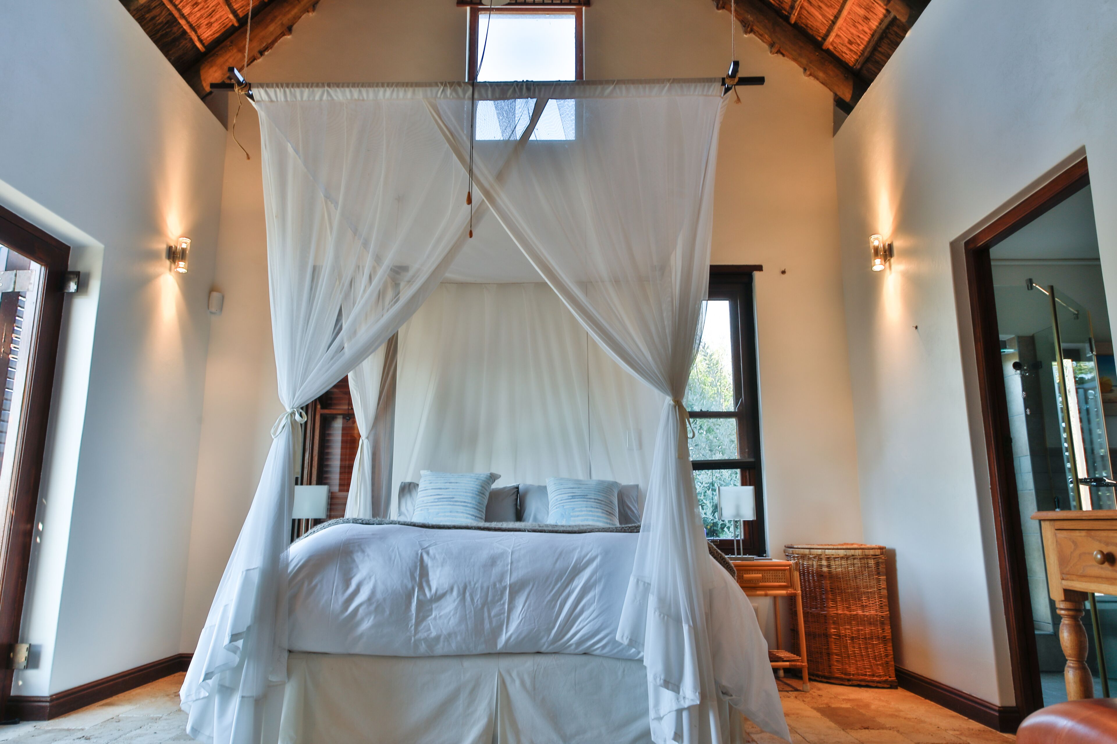Une chambre à coucher avec un lit à baldaquin, une table de chevet, une lampe et une fenêtre.