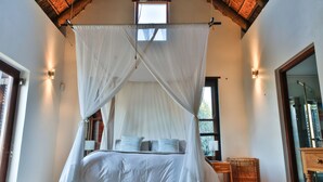 A bedroom with a four-poster canopy bed, a bedside table, a lamp, and a window. - Xairu at Le Domaine Eco-Reserve (Country living) (Montagu)
