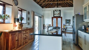 A spacious kitchen with wooden cabinets, a central island, and a large window. - Xairu at Le Domaine Eco-Reserve (Country living) (Montagu)