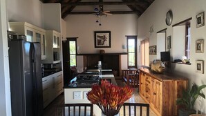 A kitchen with a refrigerator, stove, and dining table with a vase of flowers. - Xairu at Le Domaine Eco-Reserve (Country living) (Montagu)