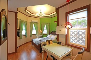 A bedroom with a bed, a table, and a window with a view. - Green Castle Pension (Pyeongchang)