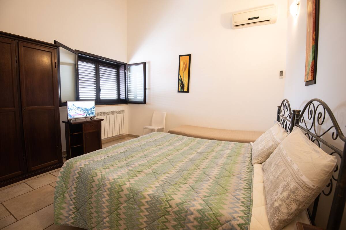 A bedroom with a bed, a desk, a chair, and a wardrobe.
