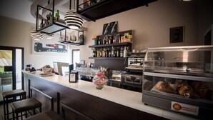 Eine moderne Bar mit Hockern, einer Kaffeemaschine und einer Vitrine mit Gebäck.